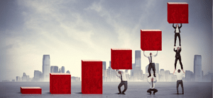 Break even in business - an image of business people trying to raise wooden blocks to make an upward progress bar